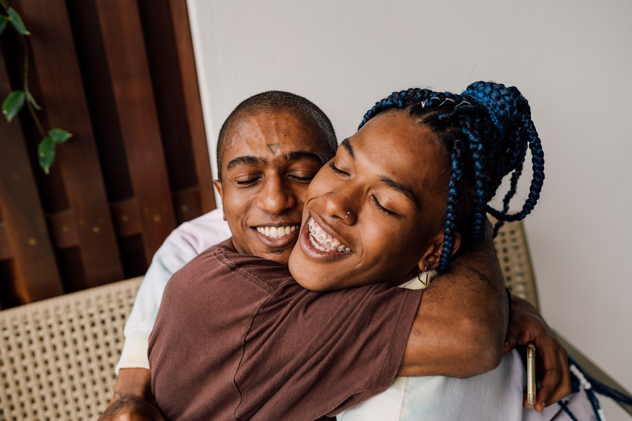 Two people with dark brown skin hug